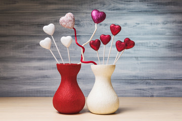 Valentines hearts in red and white jugs over wooden background