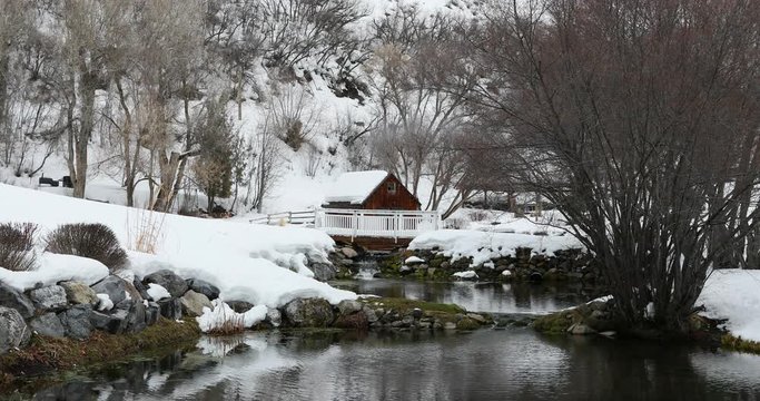 Winter mountain valley cabin on stream pond. Winter snow on landscape of central Utah. Pond, stream and cabin. Mountain valley landscape. Cold season weather. Nature and environment.