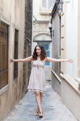 Young girl on narrow streets wearing biege dress