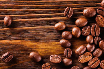 Macro image of roasted coffee beans at brown textured wooden boa