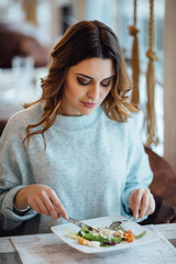 Woman eating Caesar salad in restaurant