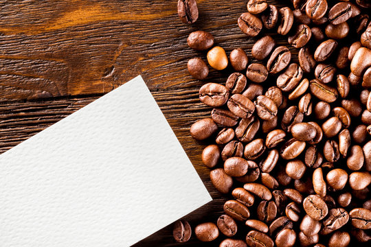 Mockup of blank business card at wooden table woth coffee beans