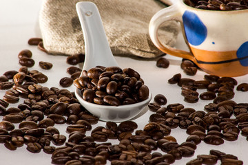 Kaffeebohnen und Kaffeetasse auf weißem Leinen mit Löffel und Jutesack