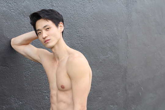 Shirtless man with a perfect body leaning on a wall