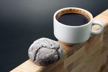 white Cup of black coffee with biscuits on a wooden frame.