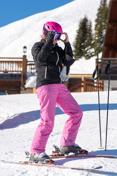 Female skier getting dressed in front of skiing hut