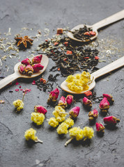 Spoons and herbs on grey background