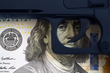 Trigger the gun on the background of the eye drawn on the banknotes. Concept of illegal arms trafficking.