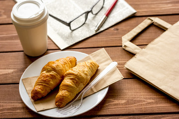 Business cup of coffee with croisant and newspaper on desk