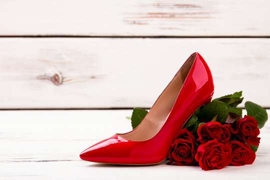 Bunch of roses and shoe. Footwear and light wooden background. Elegance in every step.