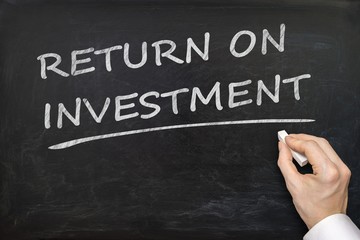 Fototapeta premium Hand is writing Return On Investment (ROI) on blackboard.