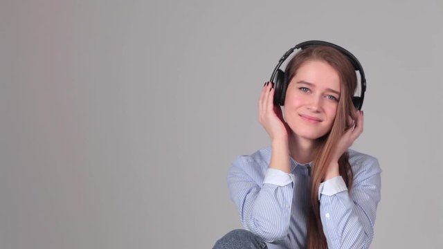 attractive girl with headphones on gray background.