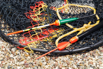 Fishing floats and fish tank on the stony ground © Vladimir Zhupanenko