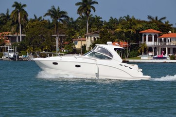 Luxury cabin cruiser on the florida intra-coastal waterway with luxury island homes in the background.