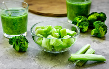 Green vegetable smoothie in glass at gray background