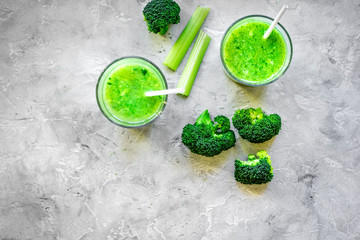Green vegetable smoothie in glass at gray background top view
