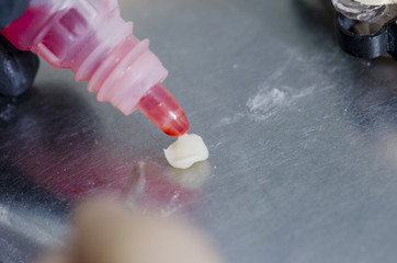 Dental technician putting an acid etching in a ceramic tooth