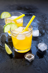 Alcohol cocktails with lime and ice on dark background