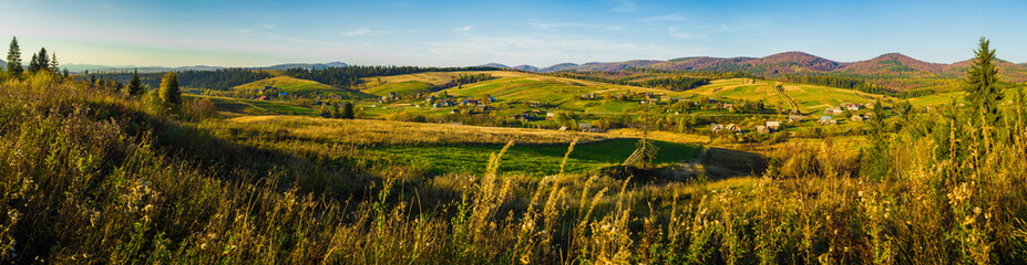 Village and autumn forest in mountains panorama.