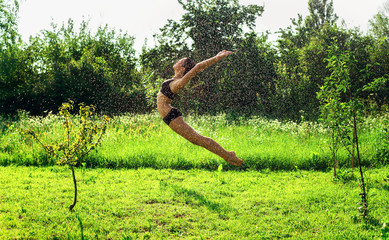 Young beautiful woman jumping in the water drops.