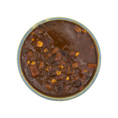 Top view of a serving of vegetable chili in an old stoneware bowl isolated on a white background.