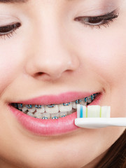 Naklejka premium Woman brushing teeth with braces using brush