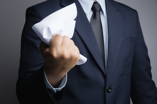 Business man hand  crunching a piece of white paper in anger