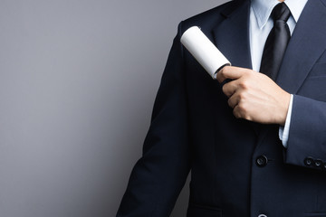 Business man cleaning his suit with adhesive lint roller