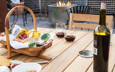 Picnic next to fire pit with two glasses of red wine and basket of bread.