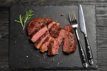 Gordijnen Medium Ribeye steak op zwarte stenen plaat © davidchukalexey