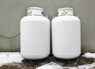 Two home propane tanks against wall. with snow on the ground 