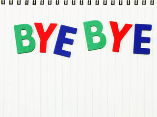 colorful wooden bye bye alphabet on notebook paper background