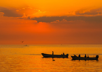 Naklejka na ściany i meble fishing boats silhouetted against a golden sunrise Sea of Cortez 