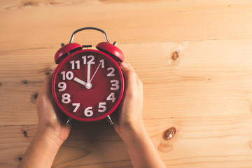 Woman's hand with red alarm clock.