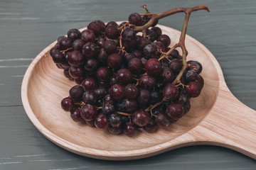 Fresh colorful healthy organic seedless red grapes gruits on wood dish.