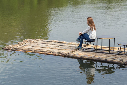 Woman sitting on a bamboo raft in river