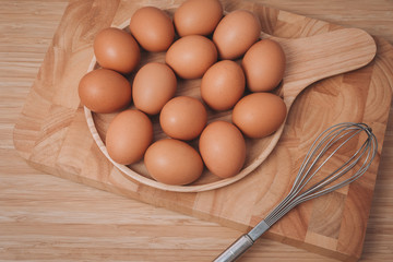 Kitchen metal wire and raw eggs on the wooden board