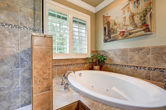 Lovely bathroom boasts jetted tub with a brown mosaic tile surround