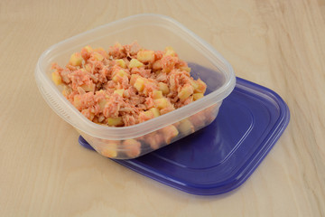 Tuna salad with apple and salad dressing in portable lunch storage container