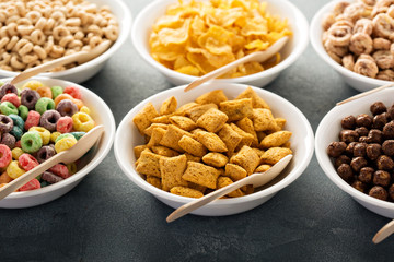 Variety of cold cereals in white bowls with spoons