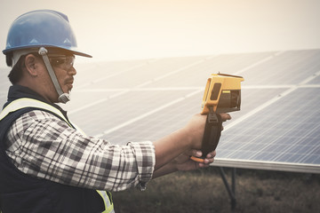 Obraz premium engineer or electrician working on maintenance equipment at industry solar power; engineer using thermal imager to check temperature heat of solar panel 