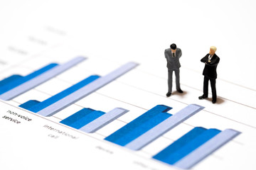 Miniature figures businessmen standing on a graph chart financia