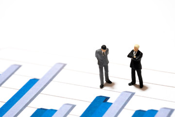 Miniature figures businessmen standing on a graph chart financia