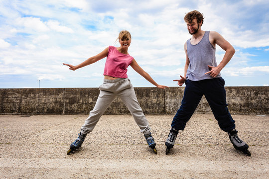 Two people exercise stretch outdoor on rollerblades.