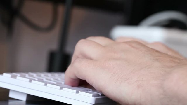 man typing on a white keyboard. hands closeup