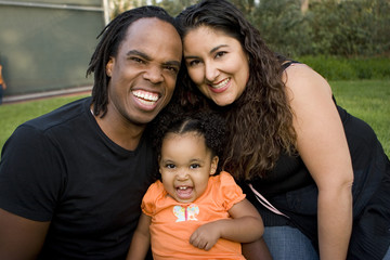 Happy biracial family smiling at a park.