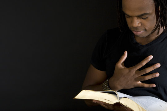 Man reading a bible isolated on black.