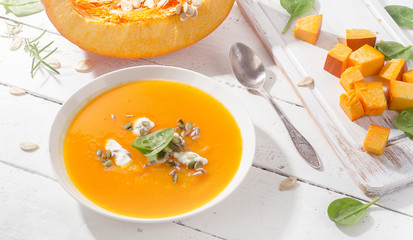 Pumpkin soup on white wooden background.