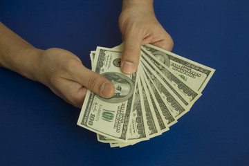 Man's hands holding dollars on dark blue background
