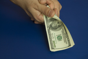 Man's hands holding dollars on dark blue background